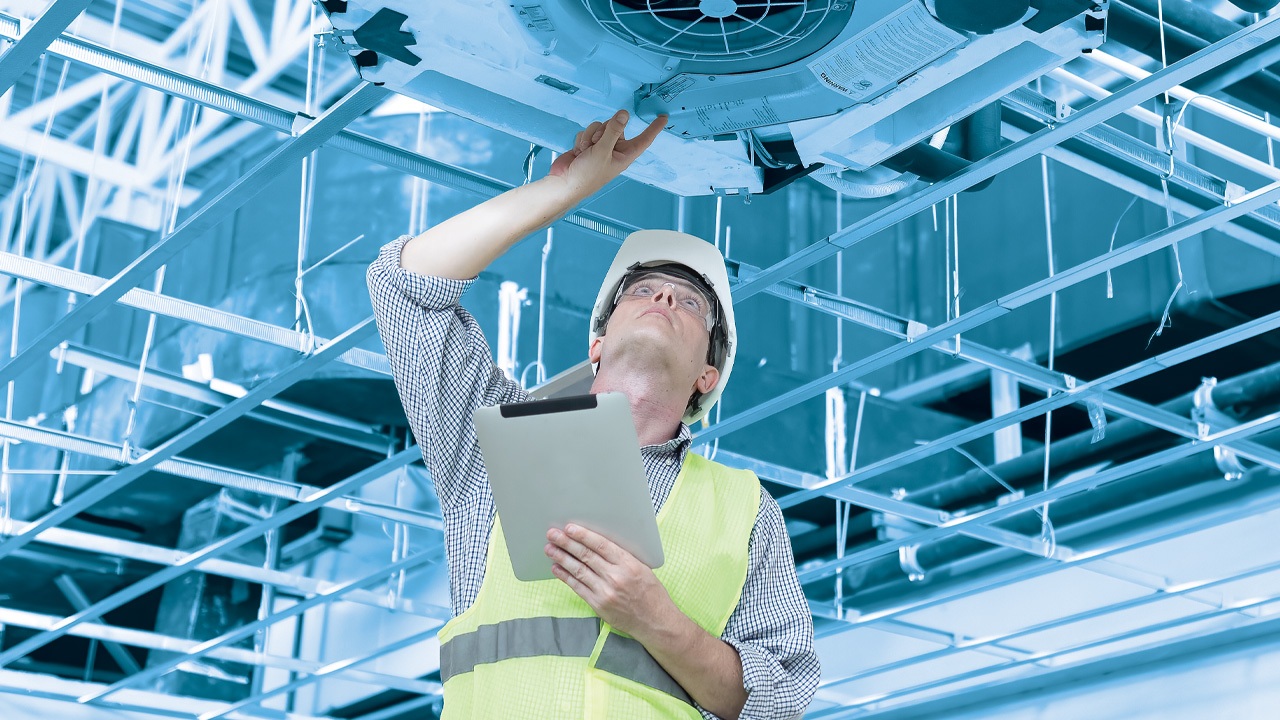 Man In Utility Vest Holding iPad Inspecting HVAC