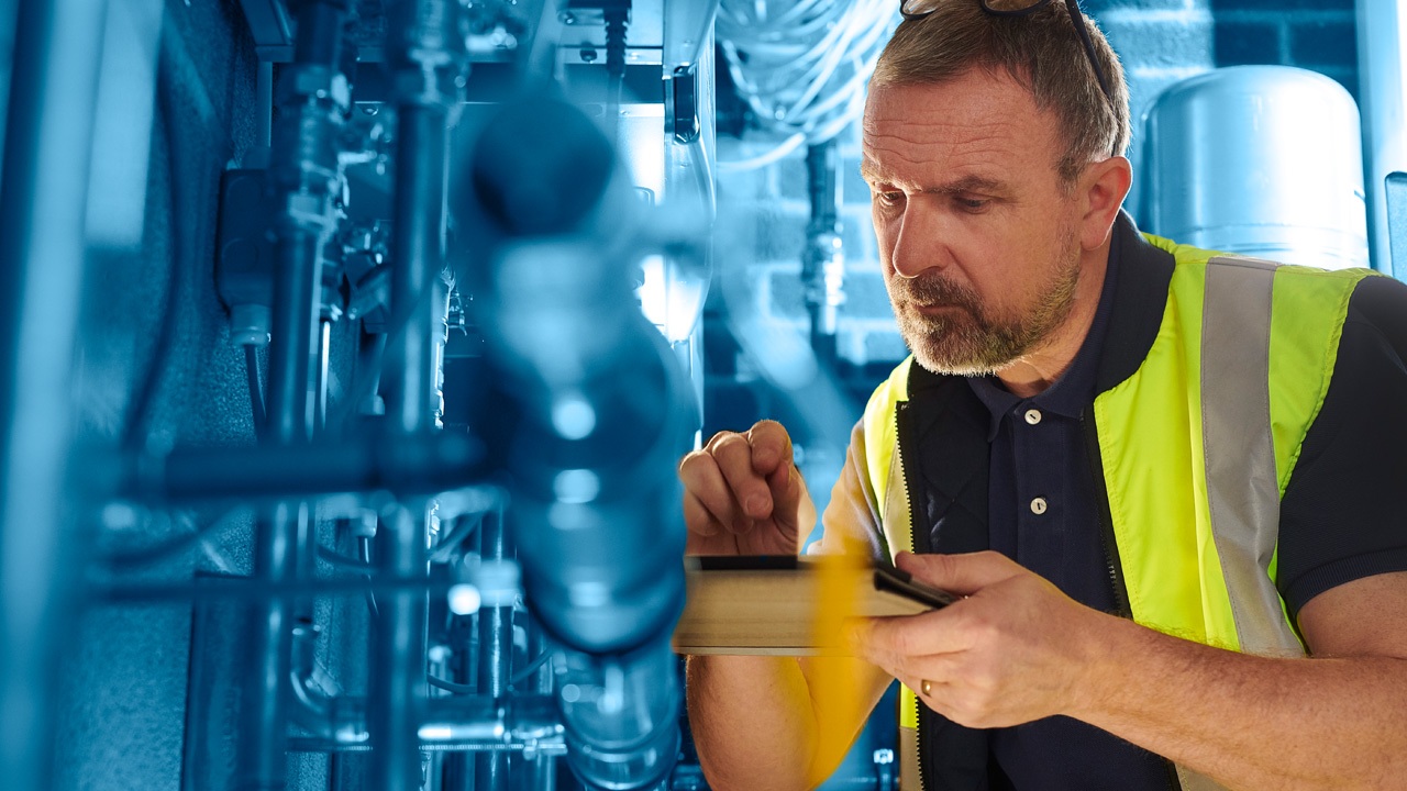 Man In Utility Vest Holding iPad Inspecting Plumbing